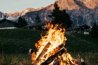 Bonfire in a meadow with mountains, an evening highlight while hiking in Switzerland.