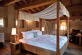 Elegant four-poster bed in a rustic hotel room in Switzerland.