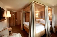 Elegant four-poster bed in a warmly lit hotel room with wooden decor.